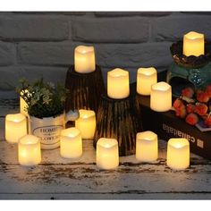 many lit candles sitting on top of a table next to a potted plant and vase