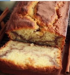 a loaf of cinnamon swirl bread on a cooling rack with cinnamon sticks next to it