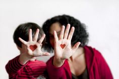 a woman holding her hands up to show two hearts on their palms and the other hand in front of her face