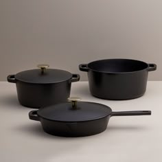 three black pots and pans on a white table