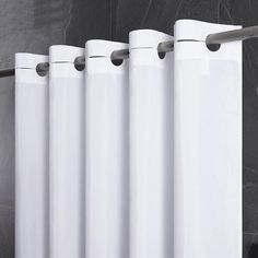 a white curtain hanging on the side of a wall next to a toilet paper dispenser