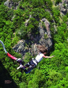 a person is flying through the air on a zip line over some trees and rocks