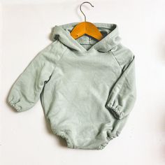 a baby bodysuit with a wooden hanger on it's neck and bottom