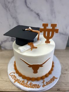 a graduation cake with a mortar and tassel on top, decorated with the university of texas symbol