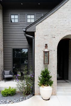 a house that has some plants in front of it and a chair next to it