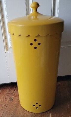 a yellow canister sitting on top of a wooden floor next to a white door