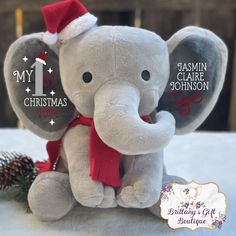 an elephant with a christmas hat and red scarf sitting on a table next to a pine cone