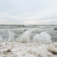 the water is splashing up on the rocks near the shore and crashing into the beach