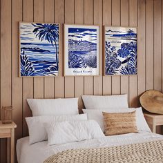 two blue and white paintings hanging on the wall above a bed in a room with wood paneling