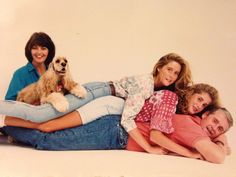 three people and a dog are laying on the floor with their arms around each other