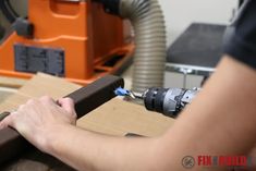 a man working on a piece of wood with a drill