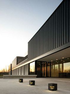 an empty courtyard in front of a building with black columns and lights on the ground