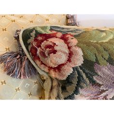 a close up of a pillow on a couch with a flower pattern and tassel