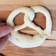 a person is making pretzels out of dough on a wooden surface with their fingers