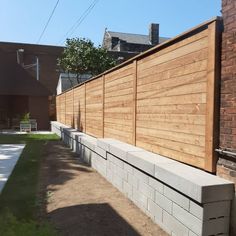 a wooden fence next to a brick wall and green grass in front of a building