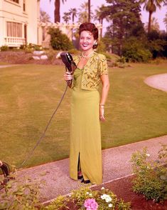 a woman holding a hair dryer in her hand and smiling at the camera while standing on a sidewalk