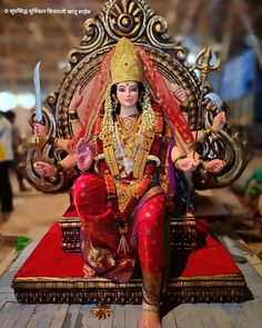 a statue of the hindu god sitting on a throne with two swords in his hand