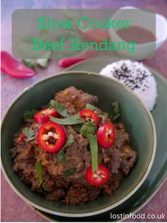 slow cooker beef rendang in a green bowl with red peppers on top