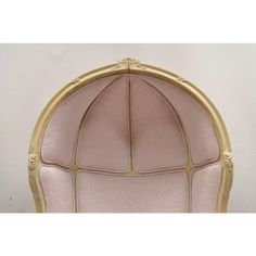 an ornate gold frame with pink leather upholstered on the back and sides, set against a white wall