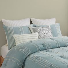 a bed with blue comforter and pillows on top of it in front of a window