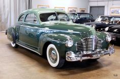 an old green car parked in a garage