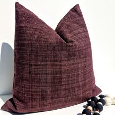 a brown pillow sitting on top of a white table next to two black and white beads