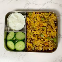 a metal container filled with food next to cucumbers and yogurt sauce