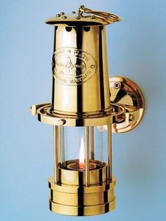 a brass wall mounted light with a candle in the center and an emblem on it