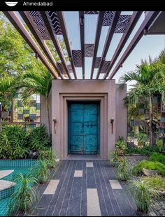 a blue door is in the middle of a garden with palm trees and other greenery