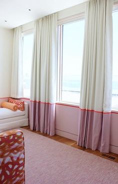 a living room filled with furniture and large windows covered in white curtained drapes