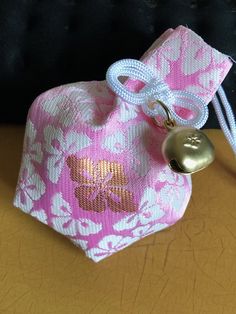 a pink and white bag with a gold bell on the front is sitting on a table