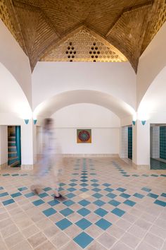 a blurry image of a person walking in a room with blue and white tiles on the floor