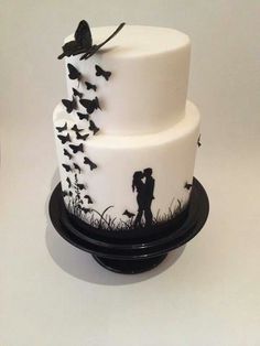 a white and black wedding cake with butterflies on it