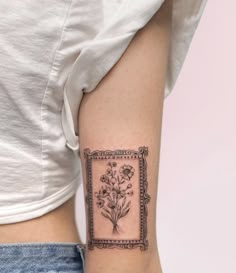 a woman's arm with a tattoo on it that has flowers in the frame