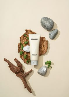 a tube of cream sitting on top of a rock next to some rocks and leaves