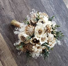 a bridal bouquet with white flowers and pine cones