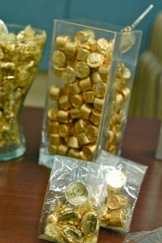 two clear vases filled with gold nuggets on top of a wooden table