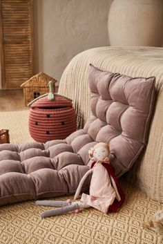 a stuffed animal is sitting on the floor next to a futon cushion and pillow