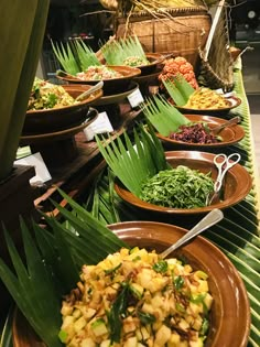 many plates of food on a table with palm leaves and baskets in the back ground