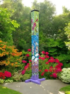 a tall purple pole sitting in the middle of a garden filled with lots of flowers