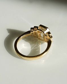 a yellow gold ring with black and white stones on the side, sitting on a table