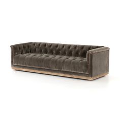 a gray velvet couch with wooden legs and buttons on the back, against a white background