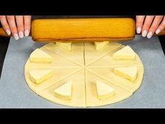 a person holding a rolling pin over a doughnut on top of a pan covered in cheese