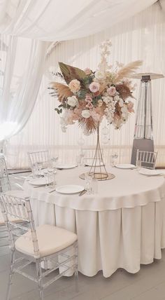 a table with white linens and flowers on it is set for a formal function