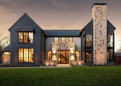 a large gray house with two story windows and stone pillars on the front of it