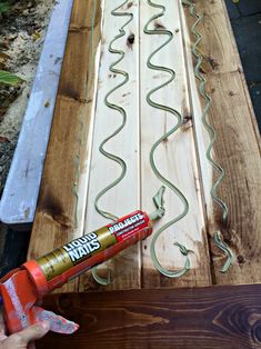 a person is using glue to paint the side of a piece of wood with green cord