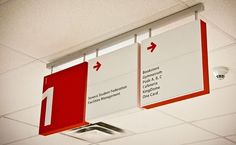 two red and white signs hanging from the ceiling in an office building or conference room