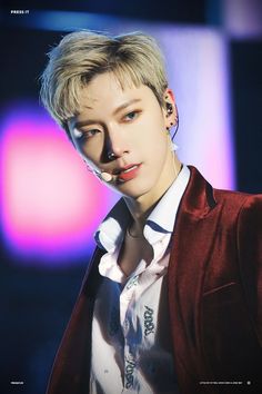 a person with short hair and piercings wearing a red jacket is looking at the camera