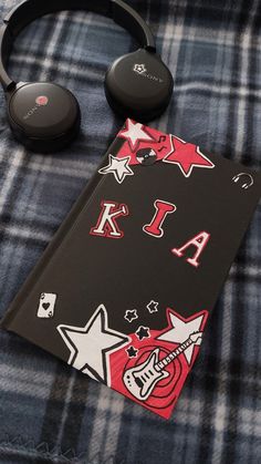 the headphones are laying next to a notebook with stickers on it's cover