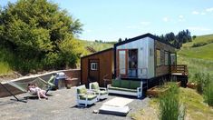 two people sitting on lawn chairs in front of a tiny house